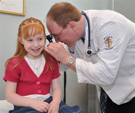 Doctor examining a smiling young girl's ears